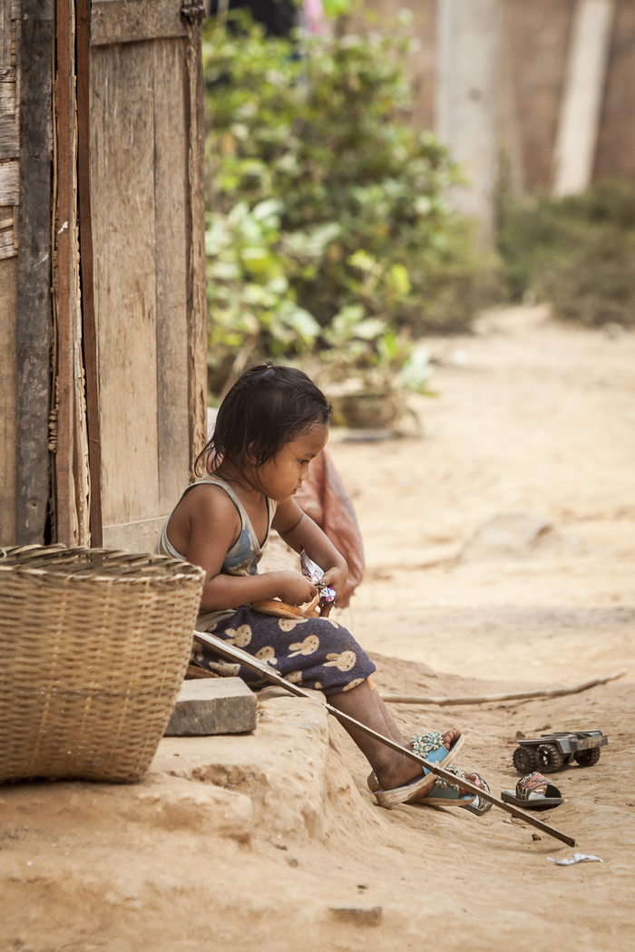 Travel photography-Little girl sitting on the stairs of her humble home- Northern Laos