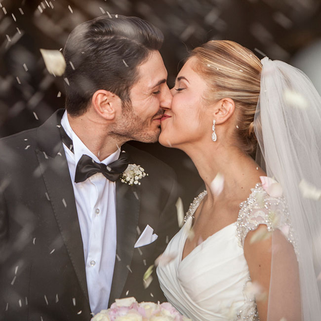 Photographie de portrait de mariage – mari et femme s’embrassent à la sortie de l’église, Les maries sous la pluie de confetti - © Massimo Municchi Photographe – Marseille – France
